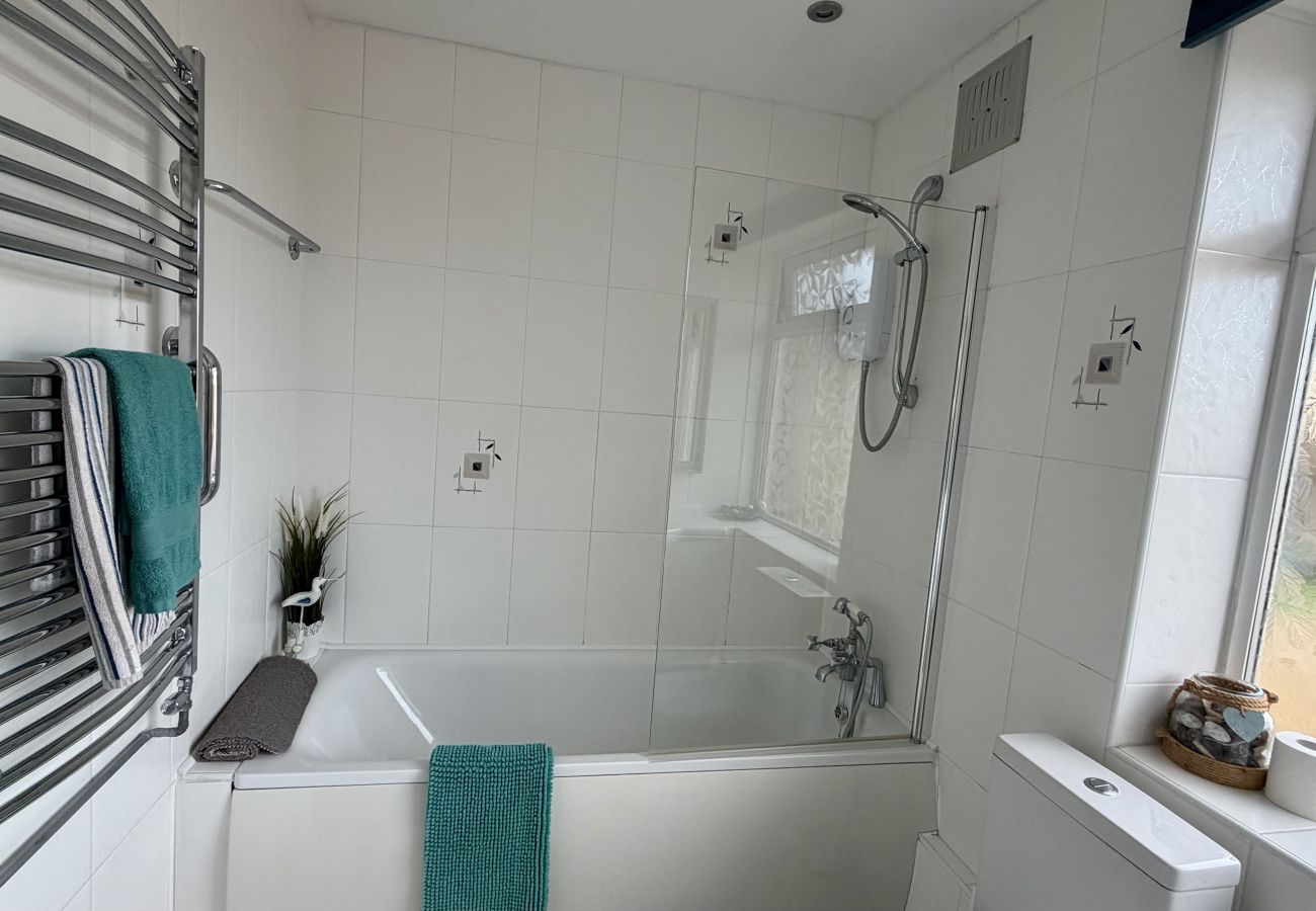 Modern bathroom with bath, shower and heated towel rail at Pheasants Haunt holiday home in Devon