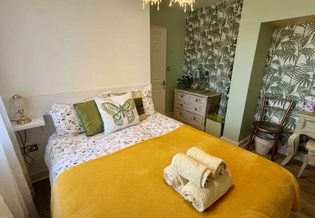 Double bedroom with green feature wall and bedside tables at Pheasants Haunt holiday home