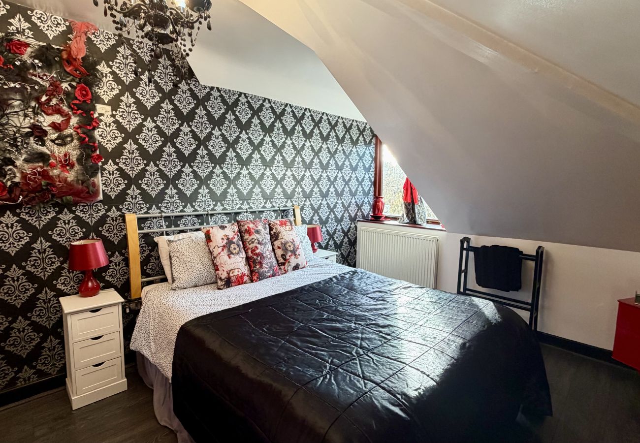 Double bed in loft bedroom with patterned feature wall at Pheasants Haunt holiday home
