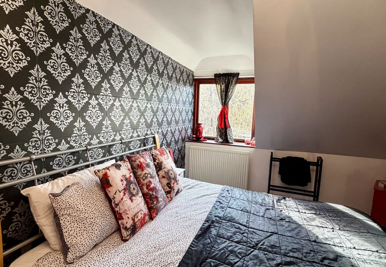 Loft bedroom with double bed and feature wallpaper at Pheasants Haunt in South Devon